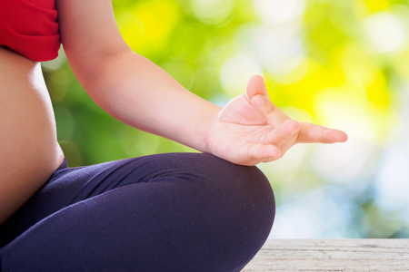 pregnant woman doing yoga with nature bokeh backgroundの写真素材