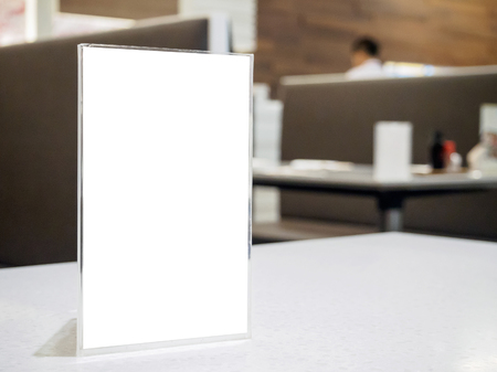 Mock up menu frame on table in the cafe restaurant, acrylic stand with white paperの写真素材
