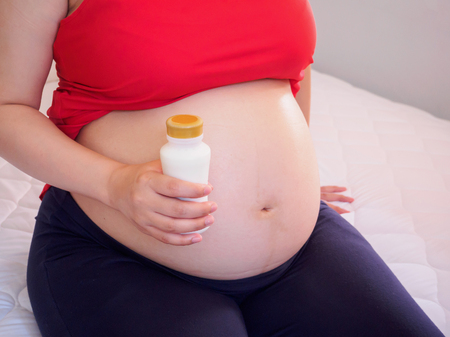 Pregnant woman holding milk bottleの写真素材