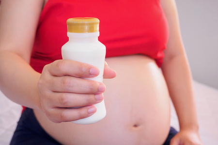 Pregnant woman holding milk bottleの写真素材