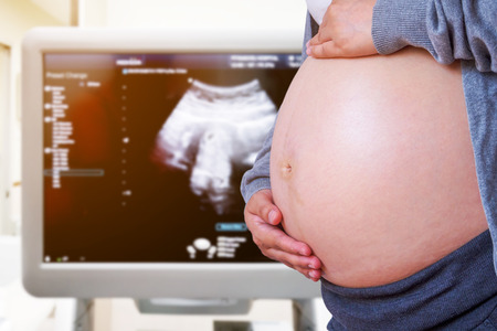 Pregnant Woman with ultrasound equipment background in hospital