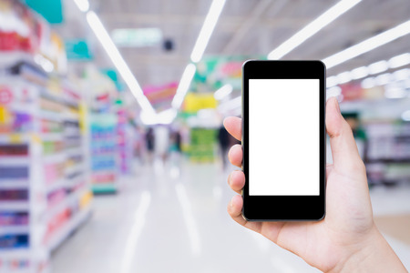 Woman using mobile smartphone while shopping in supermarket storeの写真素材