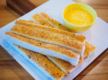 Bread sticks with sauce on wood table