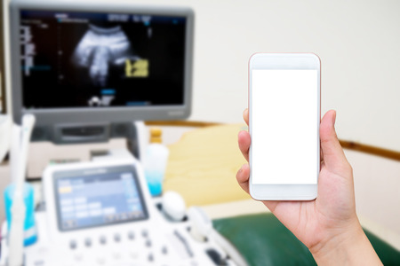 hand hold smartphone with medical room with ultrasound diagnostic equipment