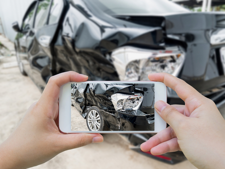 Car crash accident damaged with hand using smartphone taking photoの写真素材