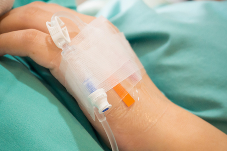 Asian woman patient hand on IV drip with saline solution, fluid replacement therapyの写真素材