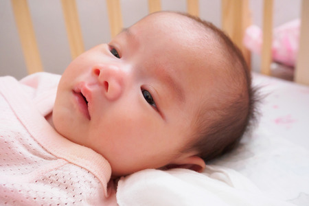 asian baby lying on bedの写真素材
