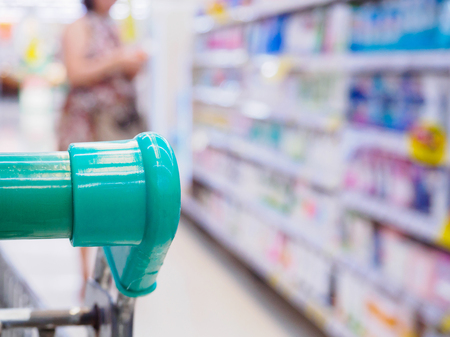 closeup shopping cart handle with customer in supermarket backgroundの写真素材