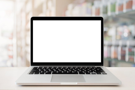 pharmacy store counter table top with blank screen laptop computer over medicine on shelves in drugstoreの写真素材