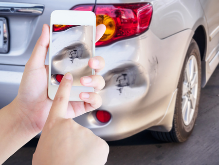 woman using mobile smartphone taking photo of car accident damaged for insuranceの写真素材