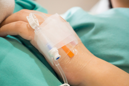 Asian woman patient hand on IV drip with saline solution, fluid replacement therapyの写真素材