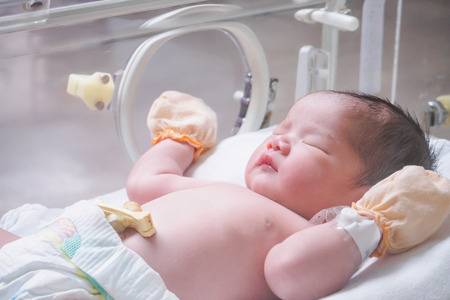 Newborn baby girl inside incubator in hospital post delivery roomの写真素材