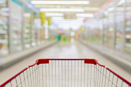 Empty red shopping cart view with milk and yogurt product shelves aisle in supermarketの写真素材