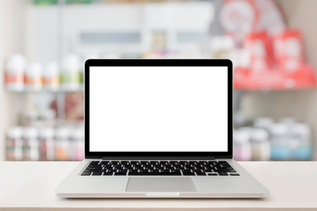 pharmacy store counter table top with blank screen laptop computer over medicine on shelves in drugstoreの写真素材
