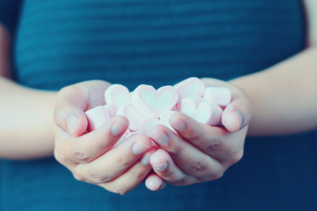 woman hand hold heart shape marshmallow for valentines dayの写真素材