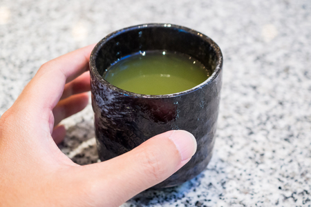 Woman hand hold Hot Green Tea cupの写真素材