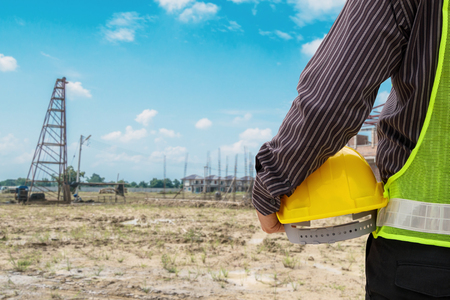 Asian business man construction engineer worker in protective helmet and blueprints paper on hand at house building siteの写真素材