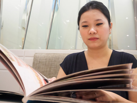 Beautiful young asian woman looking and reading food menu in luxury cafe restaurantの写真素材