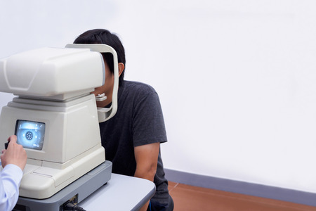Young handsome asian man take eye exam with optical eye test machineの写真素材