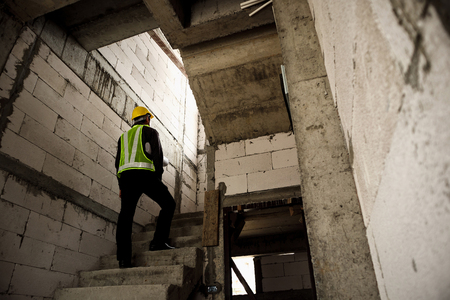 young professional engineer worker in protective helmet and blueprints paper on hand at the house building construction siteの写真素材