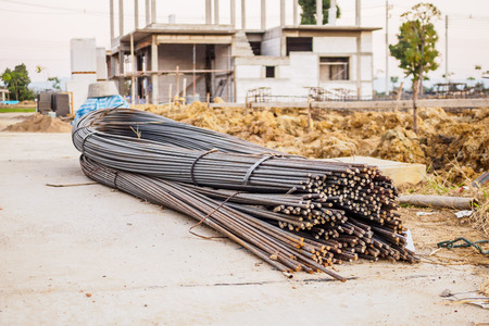 steel rebar for reinforcement concrete at construction site with house under construction backgroundの写真素材