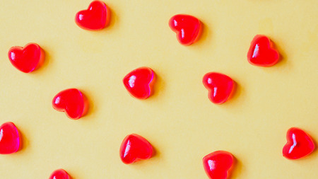 Valentines day background with red heart shape candy on yellow backgroundの写真素材