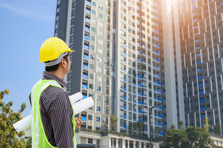 Asian business man construction engineer or architect worker with yellow protective helmet at large condominium building siteの写真素材