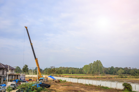 yellow telescopic arms of mobile construction crane truck at house construction siteの写真素材