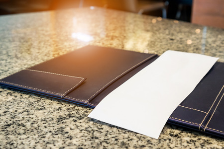 Blank empty white paper in restaurant payment billing receipt folder on granite tableの写真素材