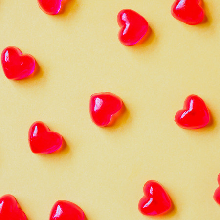 Valentines day background with red heart shape candy on yellow backgroundの写真素材