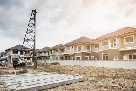 house building at construction site with pile driver and precast concrete pilesの写真素材
