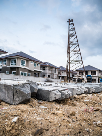 house building at construction site with pile driver and precast concrete pilesの写真素材