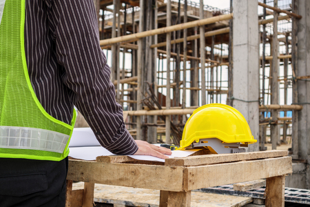young business man professional engineer worker at the house building construction site with blueprintの写真素材