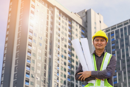 Asian business man construction engineer or architect worker with yellow protective helmet at large condominium building siteの写真素材