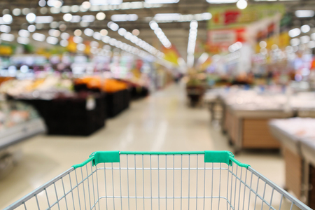 Empty shopping cart with abstract supermarket grocery store blurred defocused background with bokeh lightの写真素材
