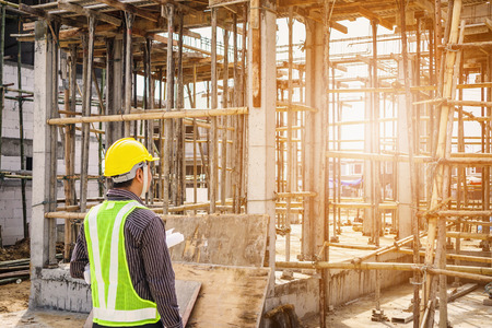 Asian business man construction engineer worker in protective helmet and blueprints paper on hand at house building siteの写真素材