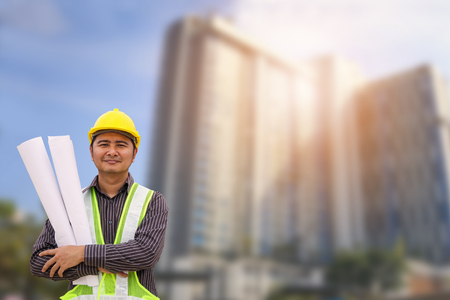 Asian business man construction engineer or architect worker with yellow protective helmet at large condominium building siteの写真素材