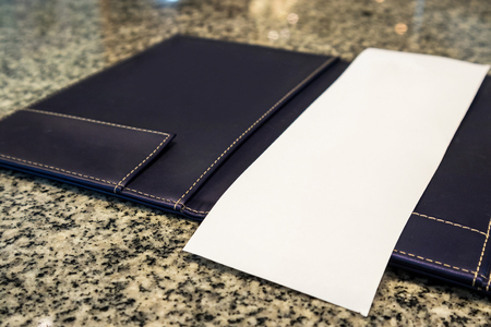 Blank empty white paper in restaurant payment billing receipt folder on granite tableの写真素材