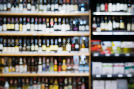 Abstract blur wine bottles on liquor alcohol shelves in supermarket or wine store backgroundの写真素材