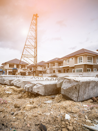 house building at construction site with pile driver and precast concrete pilesの写真素材