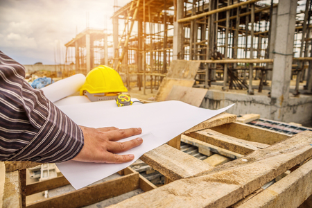young business man professional engineer worker at the house building construction site with blueprintの写真素材