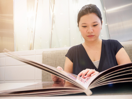 Beautiful young asian woman looking and reading food menu in luxury cafe restaurantの写真素材