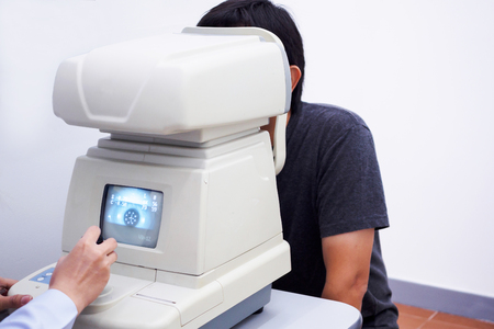 Young handsome asian man take eye exam with optical eye test machineの写真素材