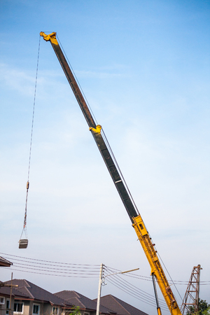 yellow telescopic arms of mobile construction crane truck lifting concrete slab to building house at construction siteの写真素材