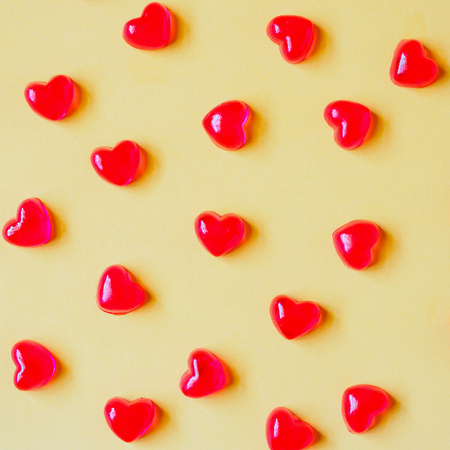 Valentines day background with red heart shape candy on yellow backgroundの写真素材