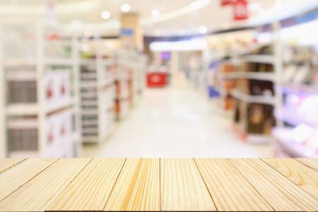 wood table with Abstract blur supermarket aisle with product shelves backgroundの写真素材