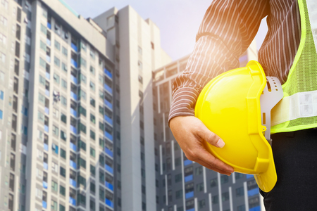 Asian business man construction engineer or architect worker with yellow protective helmet at large condominium building siteの写真素材