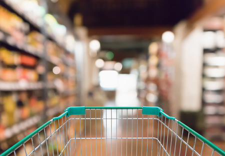 Empty shopping cart with abstract blur supermarket discount store aisle and product shelves interior defocused backgroundの写真素材