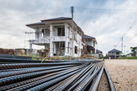 steel rebar for reinforcement concrete at construction site with house under construction backgroundの写真素材
