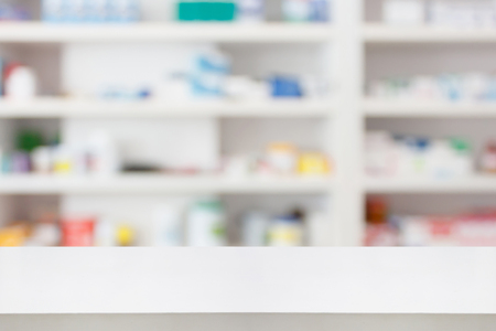 Pharmacy drugstore counter table with blur abstract backbround with medicine and healthcare product on shelvesの写真素材